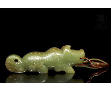 Carved jade of a green hue with brown spots due to patina from age. It shows a beast with engraved details and spiral line de