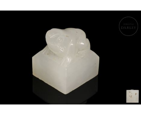 White jade carved in the shape of a small seal, with a square base, on which rests the image of a frog with its hind legs ben