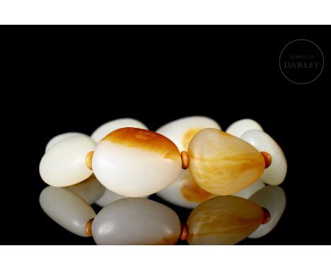 Carved jade, white and orange, with amber flecks. Carved in a triangular shape, with rounded edges and perforated on the insi