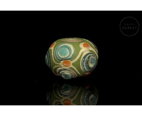 A slightly flattened bead of vitreous paste with coloured glaze, also known as ‘??’ (Liúlí). The decoration is composed of sm