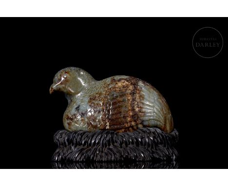 Carved jade, of a soft greenish hue with reddish and brownish flecks. It shows the massive figure of a reclining quail, with 