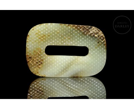 Made of light-colored carved jade with brownish and reddish flecks. It is rectangular, with rounded edges and an elongated ho