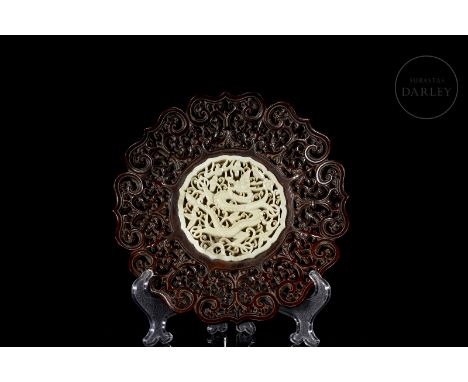 A carved white jade plaque in the form of a medallion with fine openwork details of a fierce central dragon with a sinuous, s