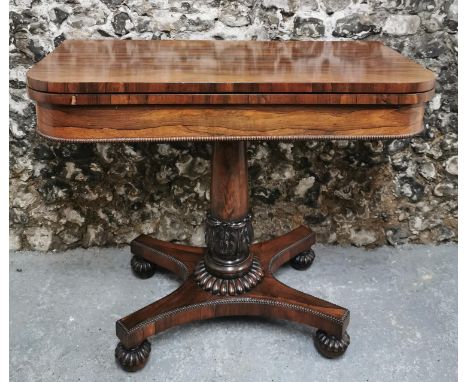 A William IV rosewood fold over card table, the rectangular top raised on a turned column, standing on a platform base with f