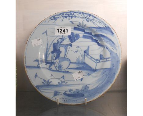 An 18th Century English Delftware plate decorated in blue with a Chinese gentleman sitting on a bench in a garden - old stapl