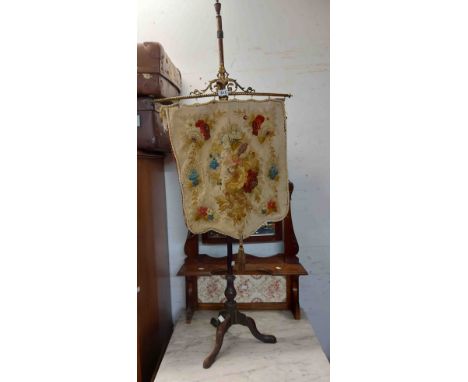 A 19th Century brass mounted mahogany pole screen with suspended floral embroidery panel, set on slender stem and tripod base