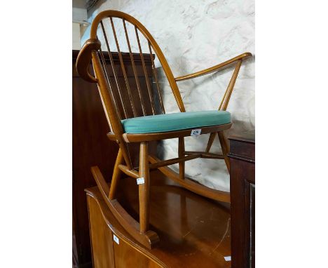 An Ercol light elm hoop stick back rocking chair with cushion and gold button label