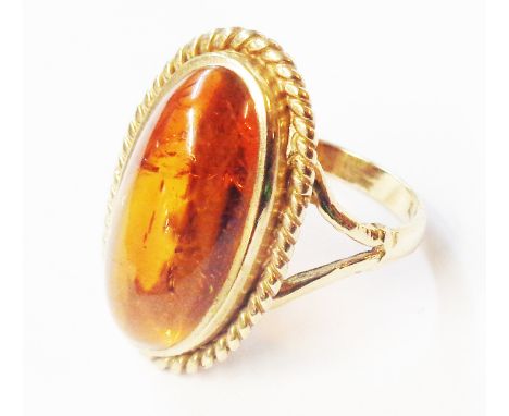 A marked 9ct. yellow metal ring, set with oval honey amber cabochon - size R
