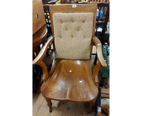 A late Victorian oak framed open armchair with button back upholstered panel and solid moulded seat, set on crinoline stretch