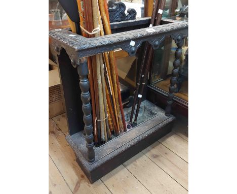 A late Victorian carved oak stick stand with bobbin turned front supports and metal drip tray