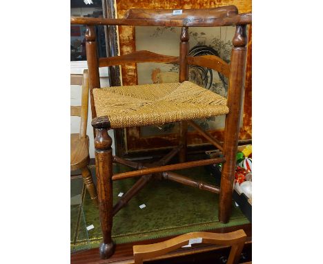 An antique stained mixed wood corner elbow chair with woven seagrass seat panel and simple turned supports - sold with a 1930