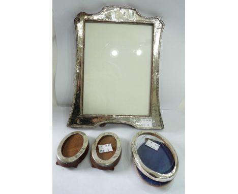 A silver fronted photograph frame with wooden easel back - sold with three small oval similar - all damaged