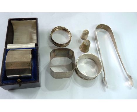 A boxed silver napkin ring - sold with three others, a pair of bright cut sugar tongs, a silver thimble and a plated similar