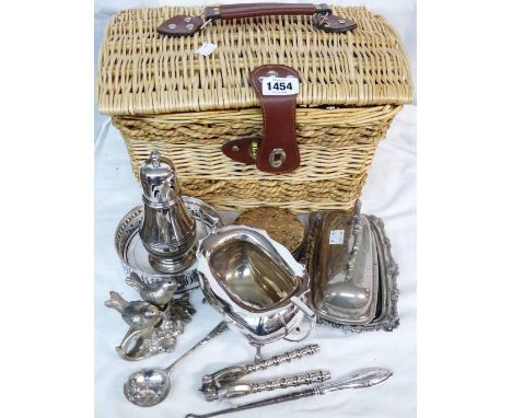 A wicker basket containing a quantity of silver plated items including butter dish, coaster and a silver handled button hook,