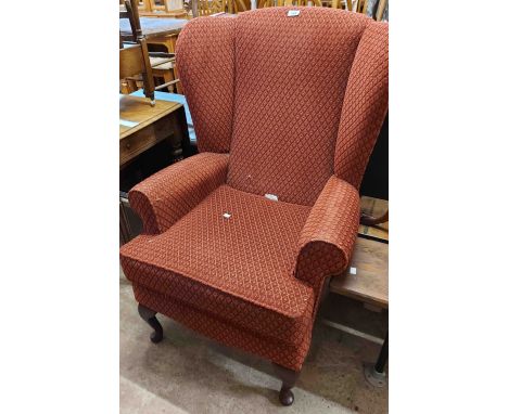A modern wing back armchair with russet/red repeat pattern machine tapestry upholstery, set on cabriole front legs with pad f