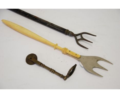 AN ANTIQUE BRASS PASTRY CUTTING WHEEL wit leaf shaped pattern maker top, an old metal BREAD FORK, with turned bone handle and