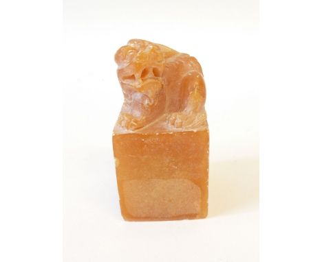 *CHINESE AMBER STAINED ALABASTER SEAL, the tall block base surmounted by a carved lion dog, 3" high, 1/2" wide