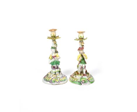 A pair of Derby candlestick figures c.1760, he standing and playing the flageolet, his companion holding a flower, each befor