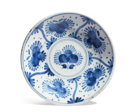 An early London delftware charger  c.1660, painted in blue with a stylized flower to the well within a panelled border of fiv