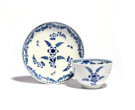 A rare Worcester blue and white teabowl and saucer  c.1780, painted with the Mimosa pattern of stylized floral sprays and gar