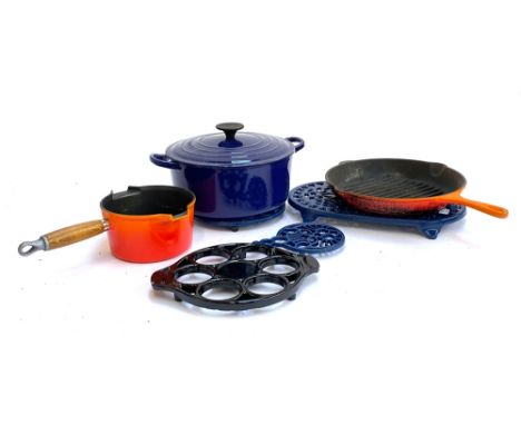 A Le Creuset casserole dish, skillet, and milk pan; together with four cast iron trivets