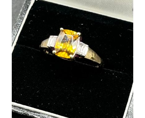 14ct yellow gold ladies ring set with a large yellow tourmaline stone off set by emerald cut diamond shoulders. [Ring size N]