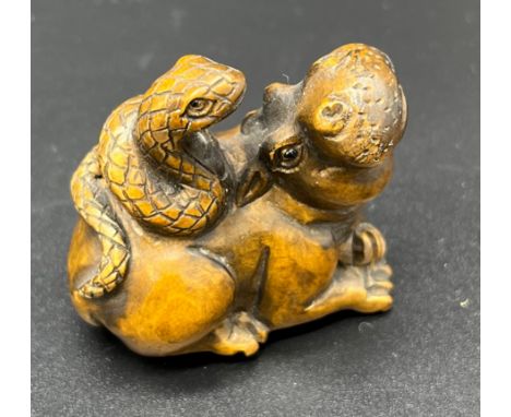 Hand carved Japanese Netsuke sculpture of a hippo resting with a snake on its back. Signed and fitted with black bead eyes. [