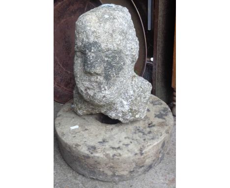 A Celtic stone head of a man, 14" tall, standing with an old grindstone