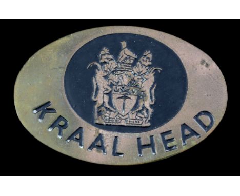 A Rhodesian Kraal Head Badge of OfficeBrass plate with lettering 'KRAAL HEAD' below the Arms in black enamel, 61mm x 40mm, lu