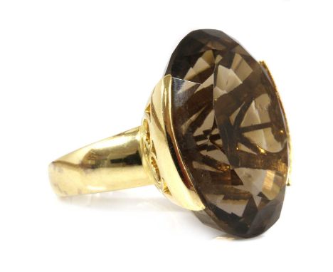 A gold single stone smoky quartz ring,with an oval mixed cut smoky quartz with a stated weight of 57.53ct, end set to a pierc