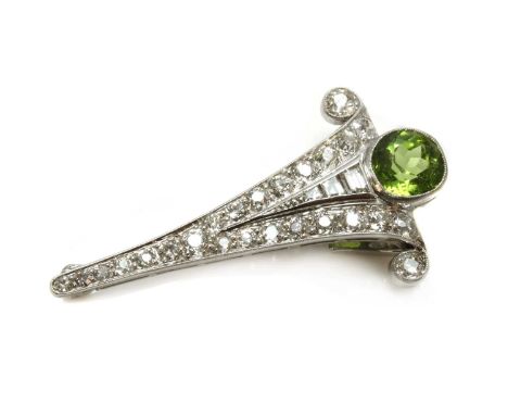 An Art Deco peridot and diamond clip brooch, with a later pin and roller catch. An arrowhead-shaped brooch, with two outer ro