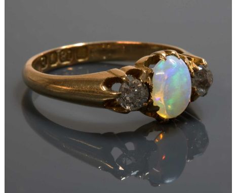 An 18ct gold late Victorian three stone opal and diamond ring,with an oval cabochon opal, claw set to the centre. An old Swis