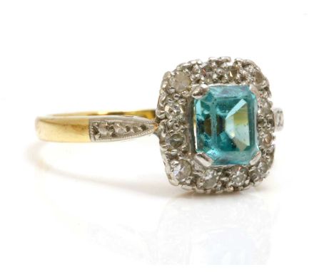 A blue zircon and diamond rectangular cluster ring,with a trap cut blue zircon, four claw set to the centre. A border of eigh