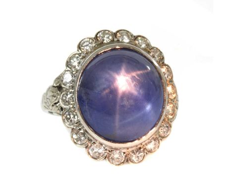An American star sapphire and diamond oval cluster ring,with an oval cabochon star sapphire, rub set to the centre. A border 
