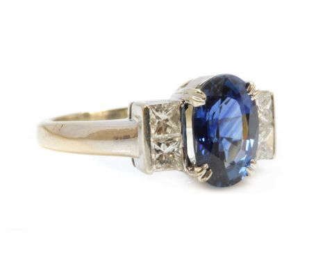 A white gold sapphire and diamond ring,with an oval mixed cut sapphire, four claw set in a plain collet. A pair of princess c