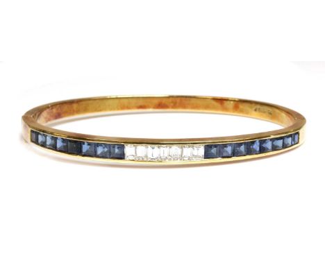 A diamond and sapphire gold hinged bangle,with a central set of seven baguette cut diamonds, with a row of graduated calibré 