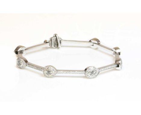 A Continental white gold diamond set bracelet,with a series of pear-shaped clusters. Each cluster composed of four princess c
