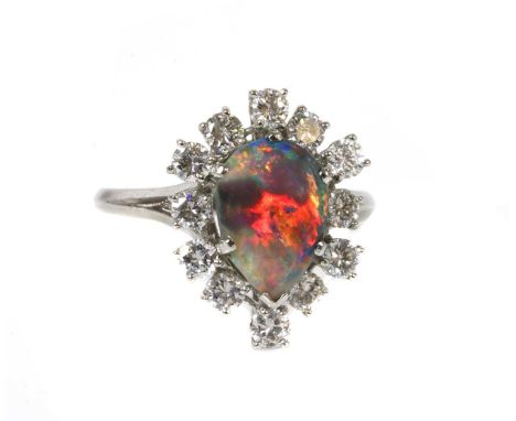 A black opal and diamond pear-shaped cluster ring,with a pear-shaped cabochon black opal, claw set to the centre. A border of