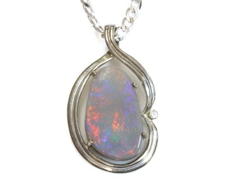 A white gold, opal and diamond pendant,with a freeform cabochon opal, four claw set to a two row frame. The scrolling pendant