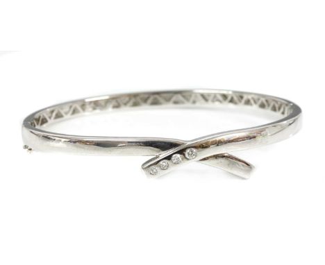 An 18ct white gold diamond set crossover bangle,with four graduated brilliant cut diamonds, Swiss set to one side, a pierced 