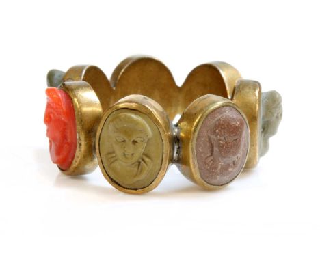A late Georgian gilt metal specimen lava and coral cameo ring,with a series of hand-carved varicoloured lava cameos and one c