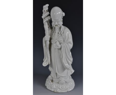 A Chinese Blanc de Chine figure, of Shou Lao, holding the peach of immortality, scroll base, 29cm high 