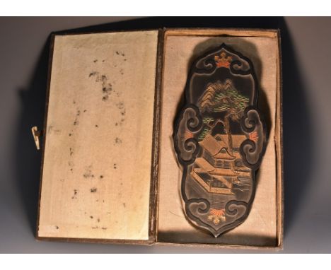 A Chinese ink cake, decorated in relief with pagodas in a monumental landscape, picked out in colours and gilt, to verso with