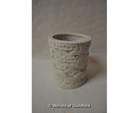 A Chinese cream porcelain brush pot decorated all over with dragons and dragon's scales, impressed mark to base, 12cm.