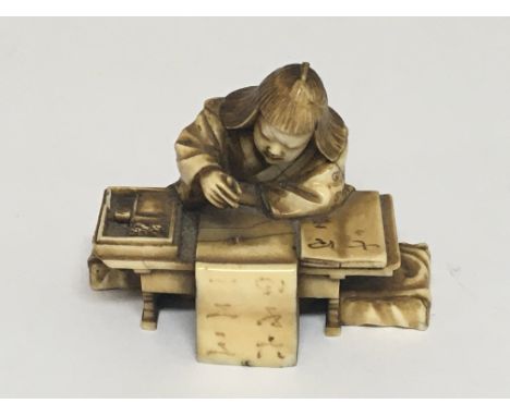 A carved 19th century ivory in the form of a scholar seated at a desk inset with a signed mother of pearl tablet. Some slight