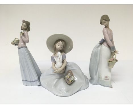 Three Lladro figures in the form of ladies.Two holding flowers and one kneeling holding a rabbit. Approx height 25 cm &lt; an