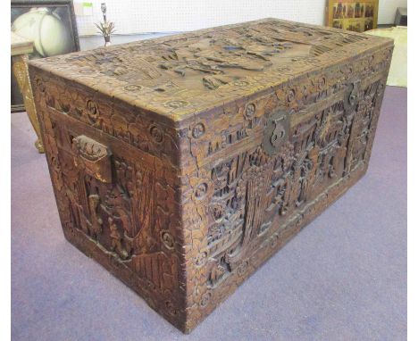 CHINESE TRUNK, ornately carved with foliate decoration and figures having a rectangular rising top enclosing a camphorwood li