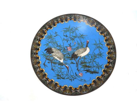 A Japanese cloisonne enamel dish of circular form, decorated with two red-capped Manchurian Cranes and floral designs on the 