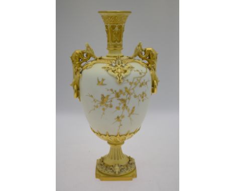 An ornate Victorian Royal Worcester ivory ground urn overlaid in gilt relief with birds in prunus, twin gilded dragon handles