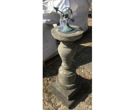 A verdigree patinated sundial raised on a weathered cast stone base